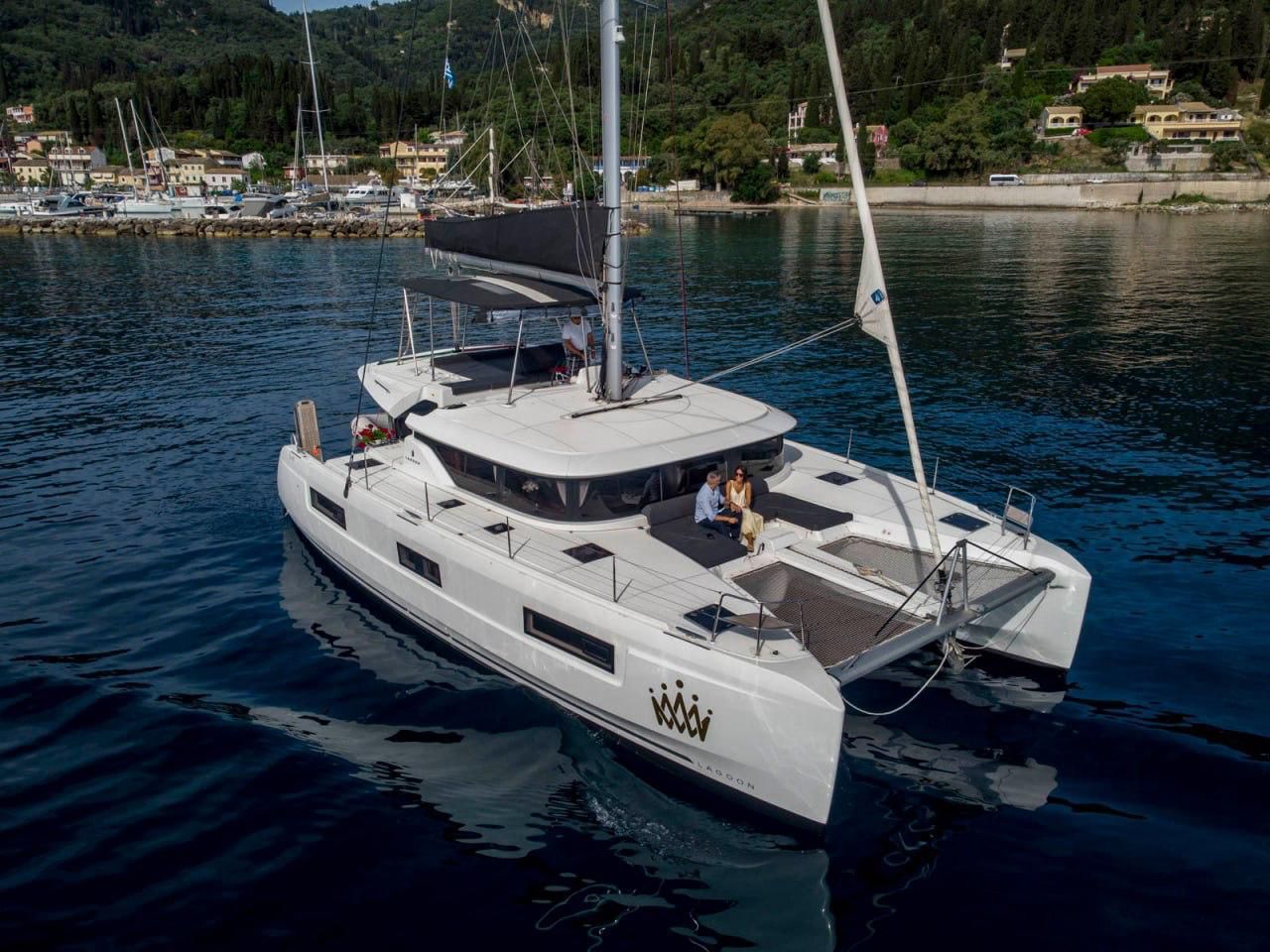 A white yacht with a covered deck, a mast, and a logo on the side.