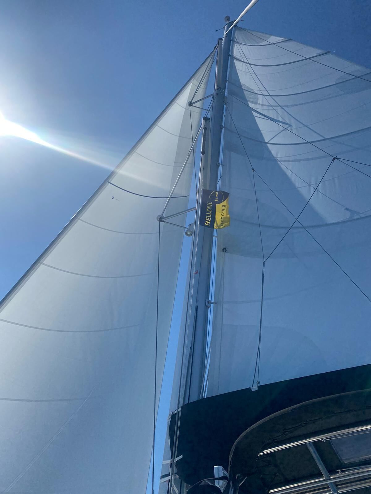 A sailboat's mast with rigging and a 'HELLENCAP' logo.