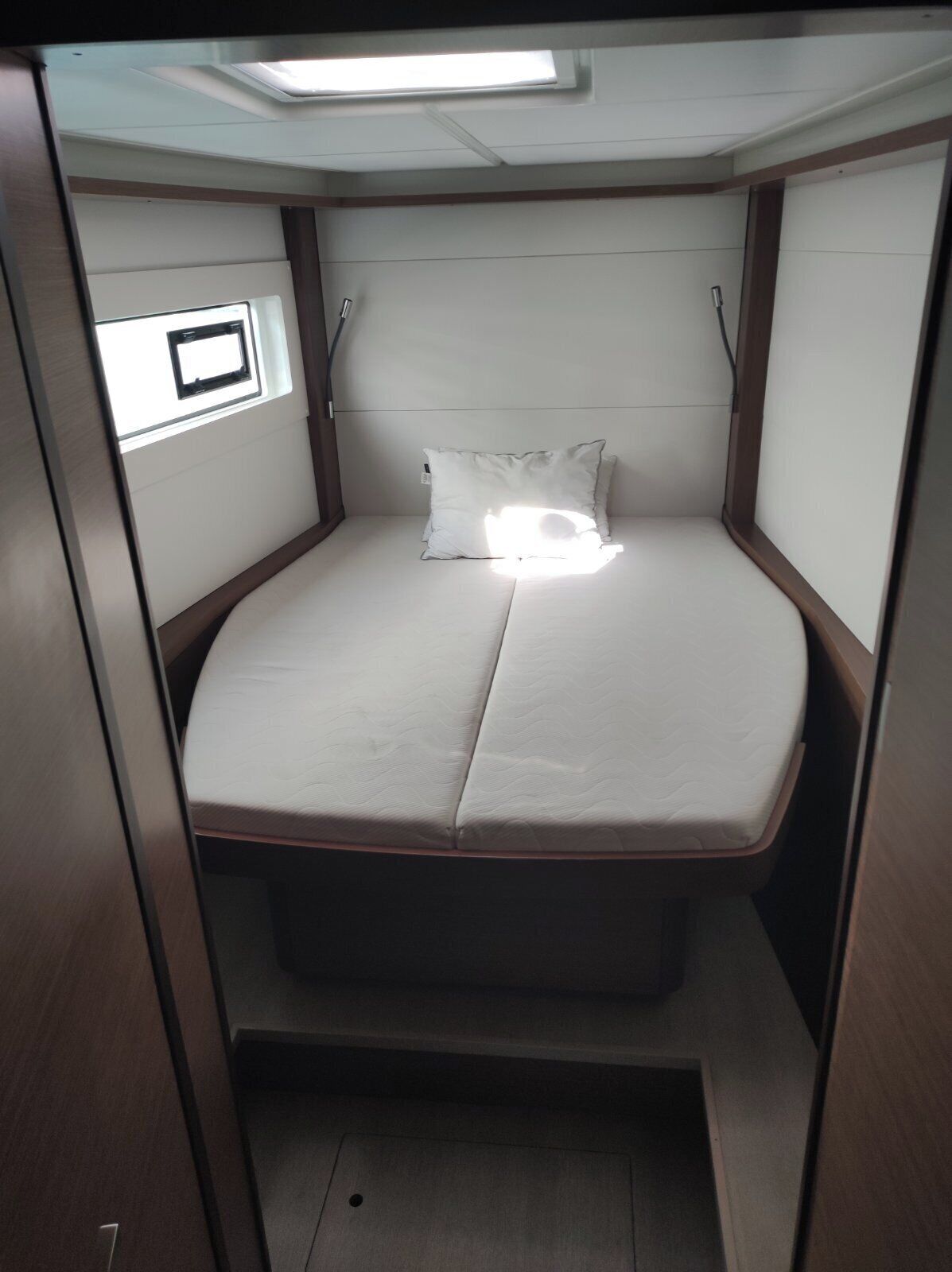 A small, enclosed sleeping area with a bed, a pillow, and a window.
