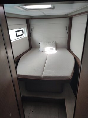A small, enclosed sleeping area with a bed, a pillow, and a window. - Sun-Kissed Sailing Adventure in the Saronic Islands (Lavrio)