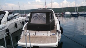 A boat docked at a marina with a covered deck, a name 'Rhea' on the side, and a 'Perfect Charter' sign. - Sun-Kissed Sailing Adventure in Northern Croatia (Punat)