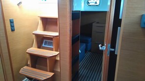 Interior compacto y bien organizado con una escalera plegable, un pequeño rincón de descanso y una kitchenette pequeña.