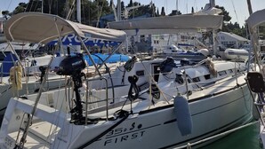 Um barco chamado '35 First' atracado em uma marina, com outros barcos e um banco por perto.