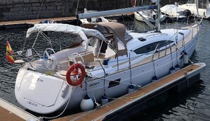 A white yacht docked at a marina with a covered deck, a steering wheel, and a lifebuoy. - Sun-Kissed Sailing Adventure in Vigo, Galicia (Vigo)