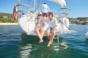 Un voilier avec un pont blanc et une personne tenant un verre.