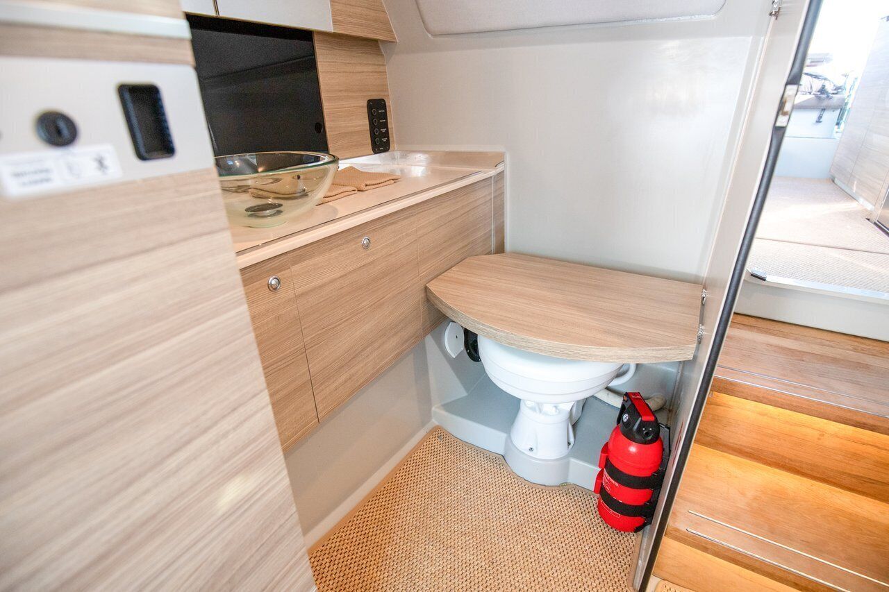 Un baño pequeño con inodoro, lavamanos y extintor rojo.