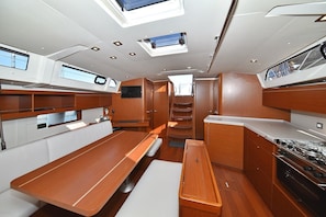 A compact kitchen with a stove, a sink, and a dining area with a bench and a table. - Sun-Kissed Sailing Adventure in Zadar, Croatia (Zadar)