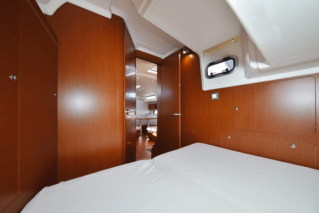 A compact, well-lit cabin with a bed, wooden walls, and a small kitchenette.