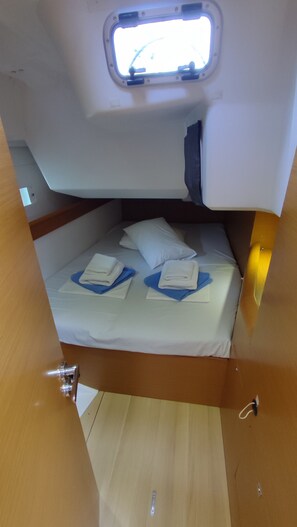 Una cabaña pequeña con una cama individual, almohadas y toallas ordenadamente dobladas.