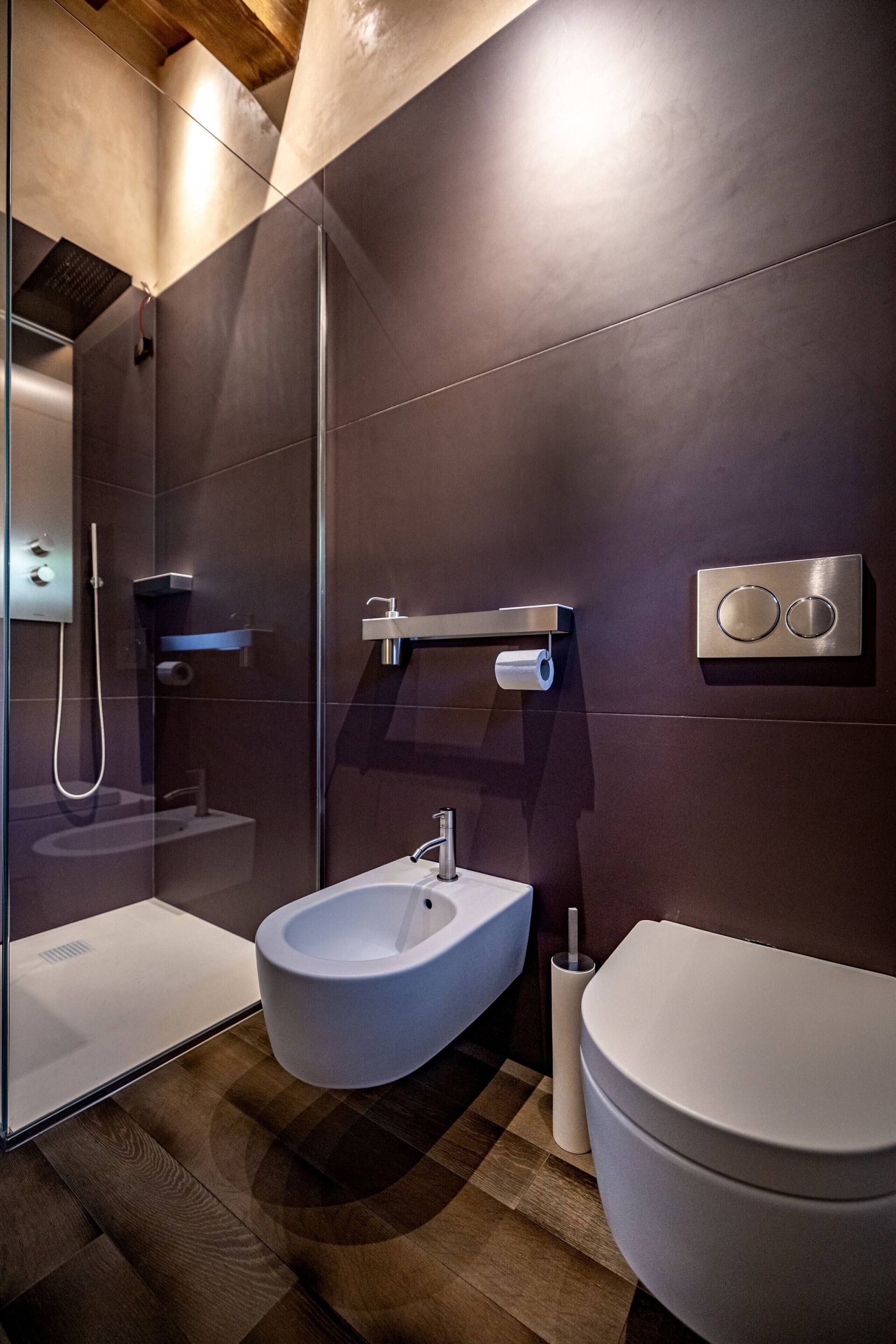 A modern bathroom with a glass-enclosed shower, a white pedestal sink, and a toilet.