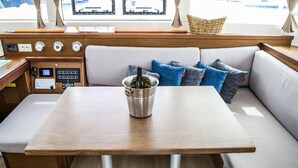 A boat interior with a wooden table, a cushioned seating area, and a control panel. - Sun-Kissed Sailing Adventure in Sibenik, Croatia (Primošten)