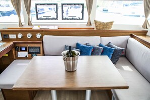 A boat interior with a wooden table, a cushioned seating area, and a control panel. - Sun-Kissed Sailing Adventure in Sibenik, Croatia (Primošten)