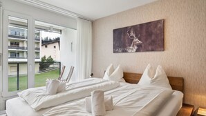 Hotellihuone, jossa on suuri sänky, taulu seinällä ja näkymä ulkopuolella olevalle parvekkeelle.