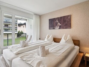 Ein Hotelzimmer mit einem großen Bett, einem Gemälde an der Wand und Blick auf den Balkon.