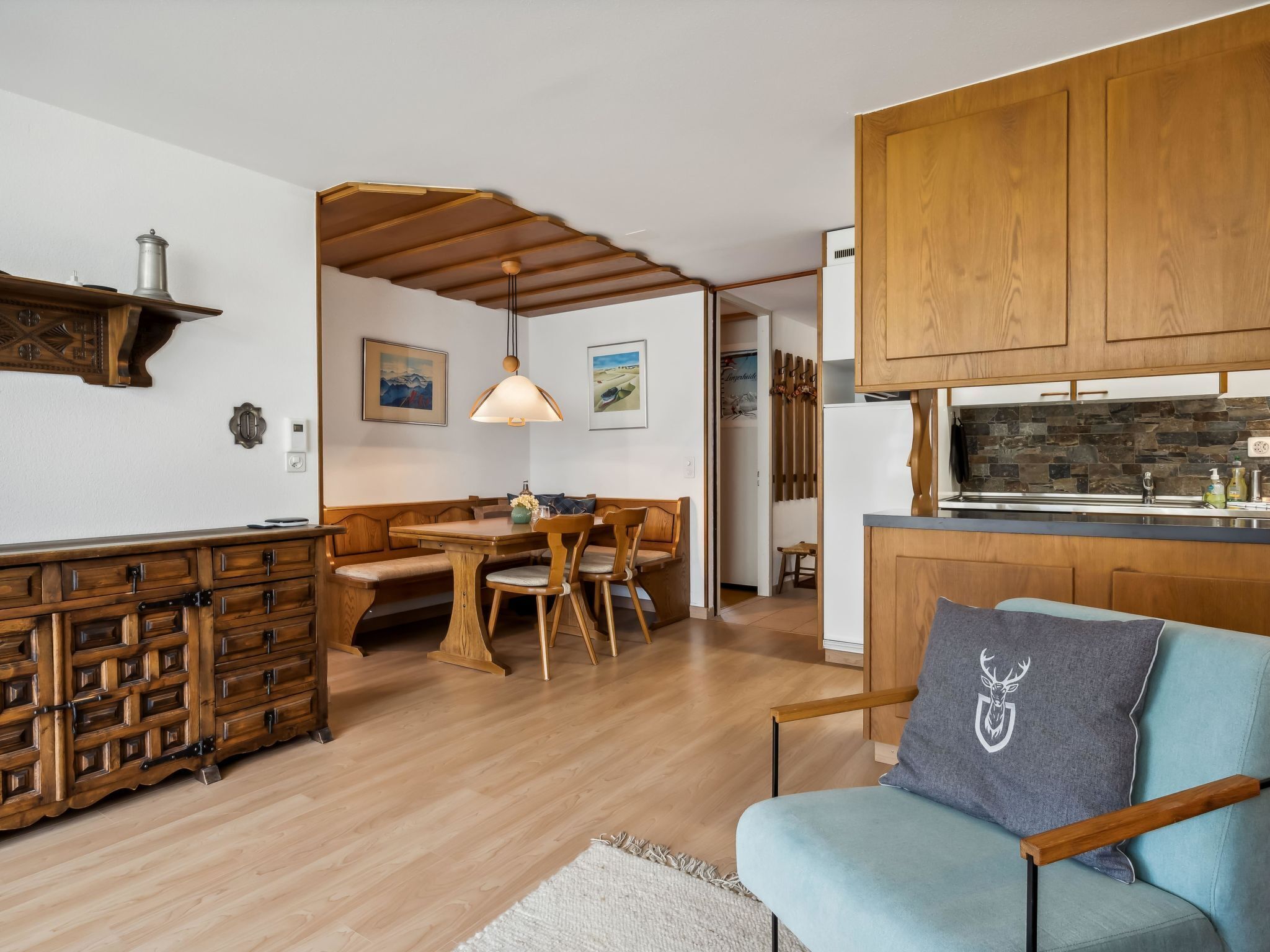 Eine moderne Küche mit Holdekor, ein Essbereich mit Tisch und Stühlen sowie eine gemütliche Sitzecke mit einer Couch.