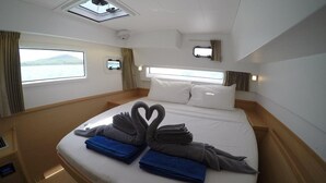 Ett hotellrum med en säng, ett fönster, en takfläkt och ett litet bord.