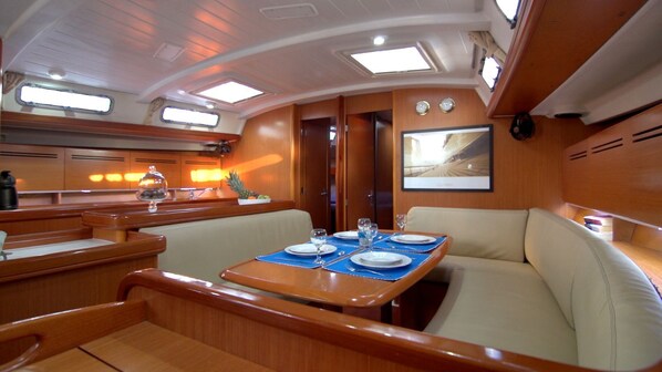 Ein Yacht-Interieur mit Essbereich, gepolsterten Sitzgelegenheiten und einem Fernseher.