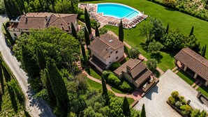 An aerial view of a property with a swimming pool, multiple buildings with tiled roofs, and well-maintained gardens. - Villa Vignola (Montaione)