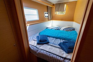 Ein kompaktes Wohnmobil-Interieur mit einem Bett, einem Fenster und einem kleinen Stauschrank.