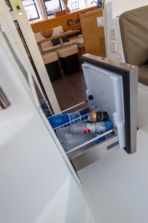 Uma kitchenette compacta com frigorífico, uma pia pequena e um espaço de refeições com mesa e cadeiras.