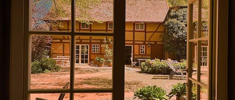 A traditional half-timbered house with a courtyard, a wooden bench, and potted plants.