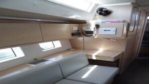 A compact interior with a cushioned seating area, a small kitchenette, and a fan on the wall. - Sun-Kissed Sailing Adventure in Phuket (Mai Khao)