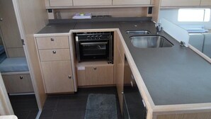 A compact kitchen with a built-in oven, a sink, and a small countertop. - Sun-Kissed Sailing Adventure in Phuket (Mai Khao)