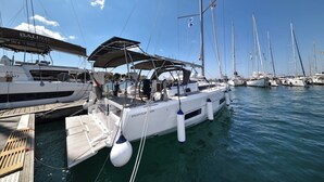 Een jachthaven met verschillende zeilboten afgemeerd, waaronder een witte boot genaamd 'BALIO' en een andere genaamd 'DUFOUR 470'.