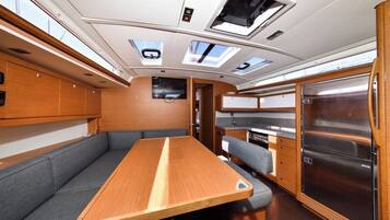 A compact interior with a dining table, seating, a kitchen area, and a refrigerator.