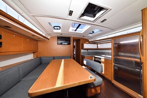 A compact interior with a dining table, seating, a kitchen area, and a refrigerator. - Sun-Kissed Sailing Adventure in Zadar, Croatia (Zadar)