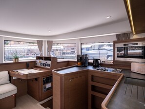 A compact kitchen with a coffee maker, kettle, and a built-in oven. - Dubrovnik Delight: A Sun-Kissed Sailing Experience (Komolac)