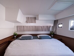 A bedroom with a large bed, two bedside tables, a window, and a ceiling light. - Dubrovnik Delight: A Sun-Kissed Sailing Experience (Komolac)