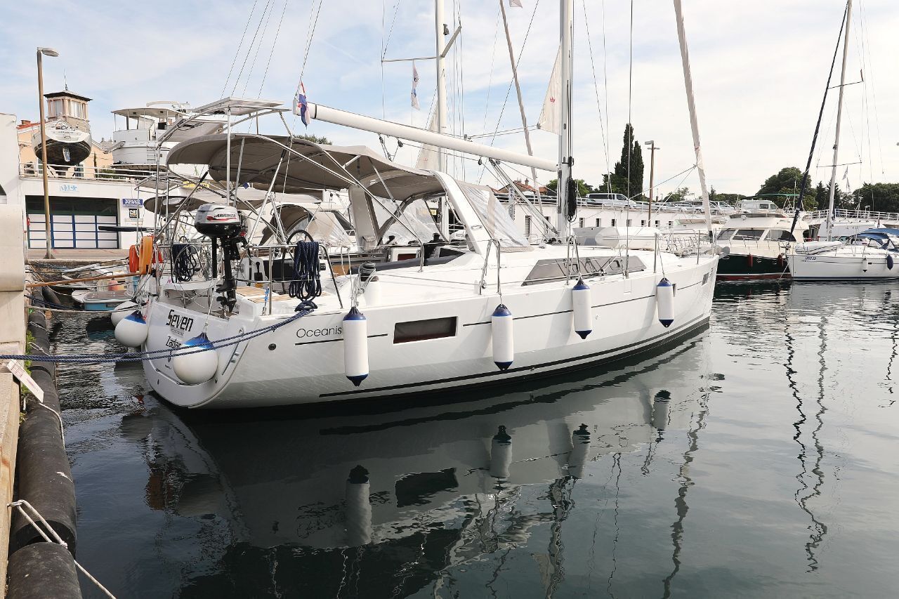 Un port de plaisance où sont amarrés plusieurs voiliers, avec une terrasse couverte et une cabine dotée d’une fenêtre.