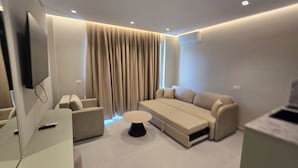 Una sala de estar moderna con un sofá, sillones, una mesa de centro y un televisor de pantalla plana.