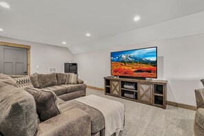 Ein Wohnzimmer mit Ecksofa, Flachbildfernseher und einer Holzunterhaltungsecke.