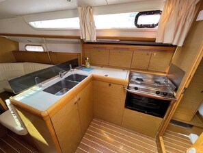 A compact galley with a sink, stove, and storage cabinets. - Sun-Kissed Sailing Adventure in Split-Dalmatia, Croatia (Vinišce)
