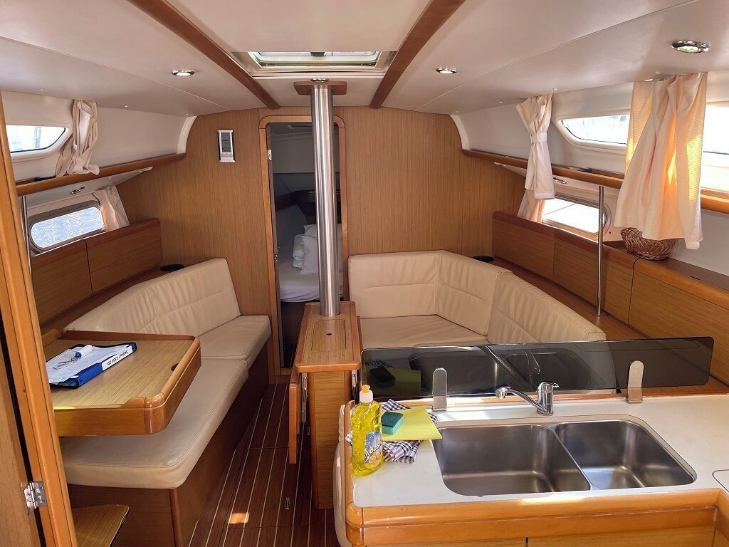 A compact galley with a sink, storage cabinets, and a small seating area.