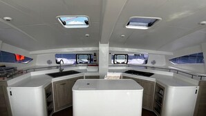 A modern kitchen with a central island, two windows, and a view of the sea. - Sun-Kissed Sailing Adventure in Phuket (Mai Khao)