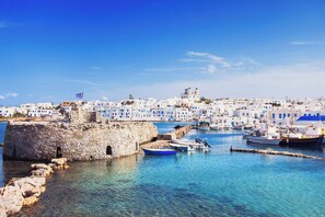 A coastal town with stone buildings, a clear blue sky, and boats in the harbor.