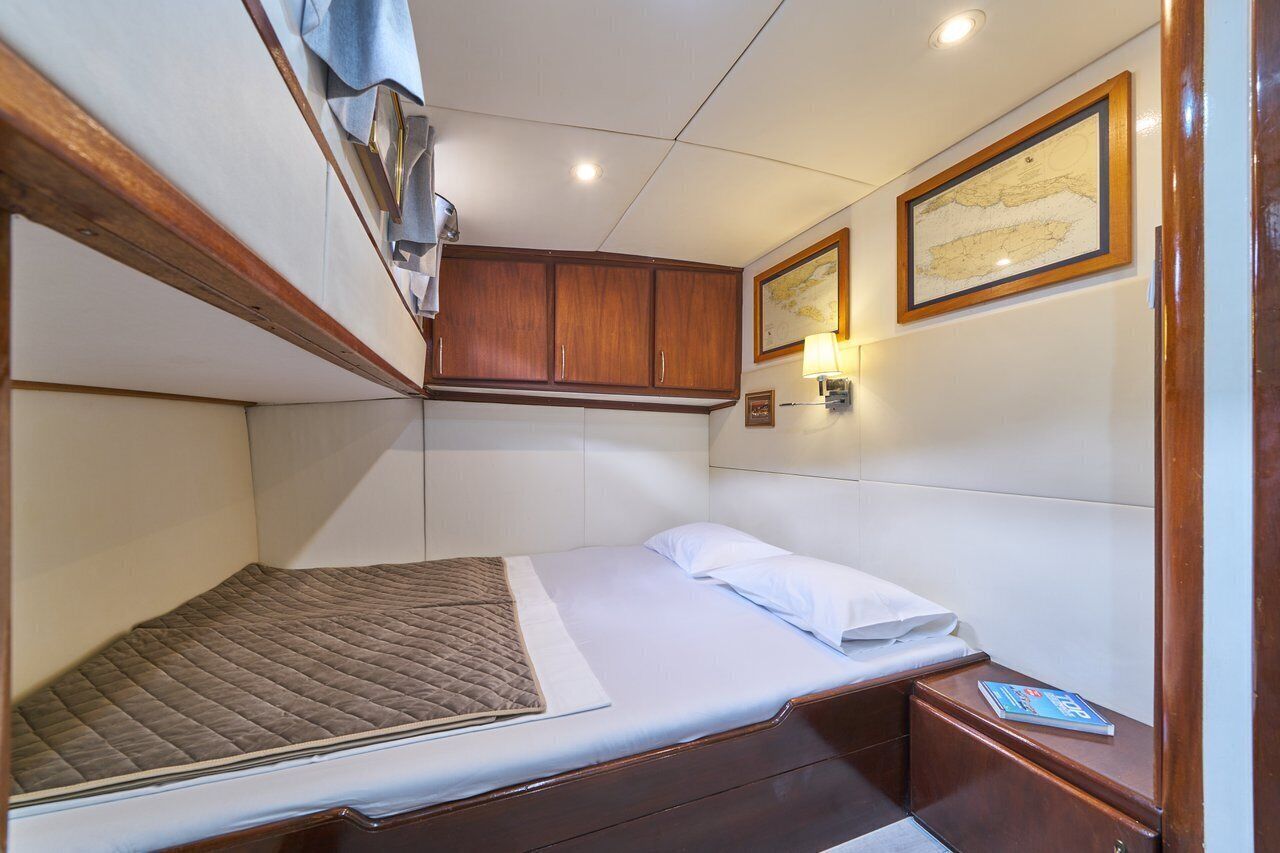 Um quarto compacto com beliche, uma cama de solteiro, armários de madeira e quadros nas paredes.