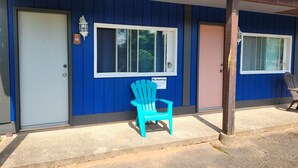 Un edificio de color azul, con dos puertas y una silla azul afuera.