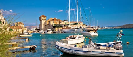 Un puerto con barcos, un edificio histórico con una torre y aguas tranquilas.