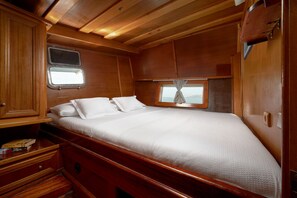 A wooden cabin interior with a bed, a window, and a small cabinet.