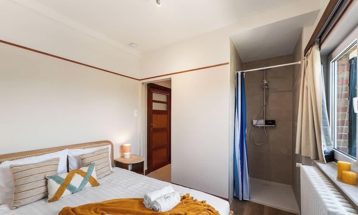 A bedroom with a bed, bedside table, and a window with curtains.