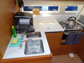 A compact kitchen with a sink, a coffee maker, a kettle, and a stove. - Sun-Kissed Sailing Adventure in Sibenik, Croatia (Primošten)
