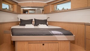 Ein modernes Schlafzimmer in einem Wohnmobil mit einem Bett, zwei Kissen, einem Nachttisch und einem Fenster.