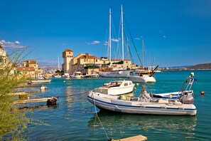 A harbor with boats, a historic building with a tower, and calm waters.