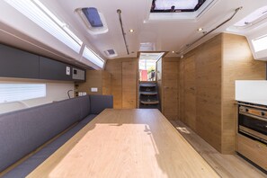 A compact kitchen with wooden cabinets, a built-in oven, and a bench seating area. - Sun-Kissed Sailing Adventure in Zadar, Croatia (Zadar)