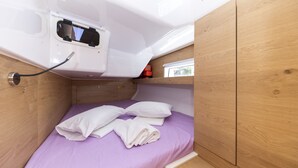 A compact room with a bed, a small window, and a white electrical outlet. - Sun-Kissed Sailing Adventure in Zadar, Croatia (Zadar)