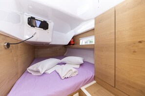 A compact room with a bed, a small window, and a white electrical outlet. - Sun-Kissed Sailing Adventure in Zadar, Croatia (Zadar)